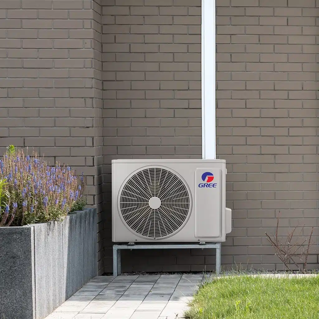 Outdoor heat pump unit installed against a brick wall